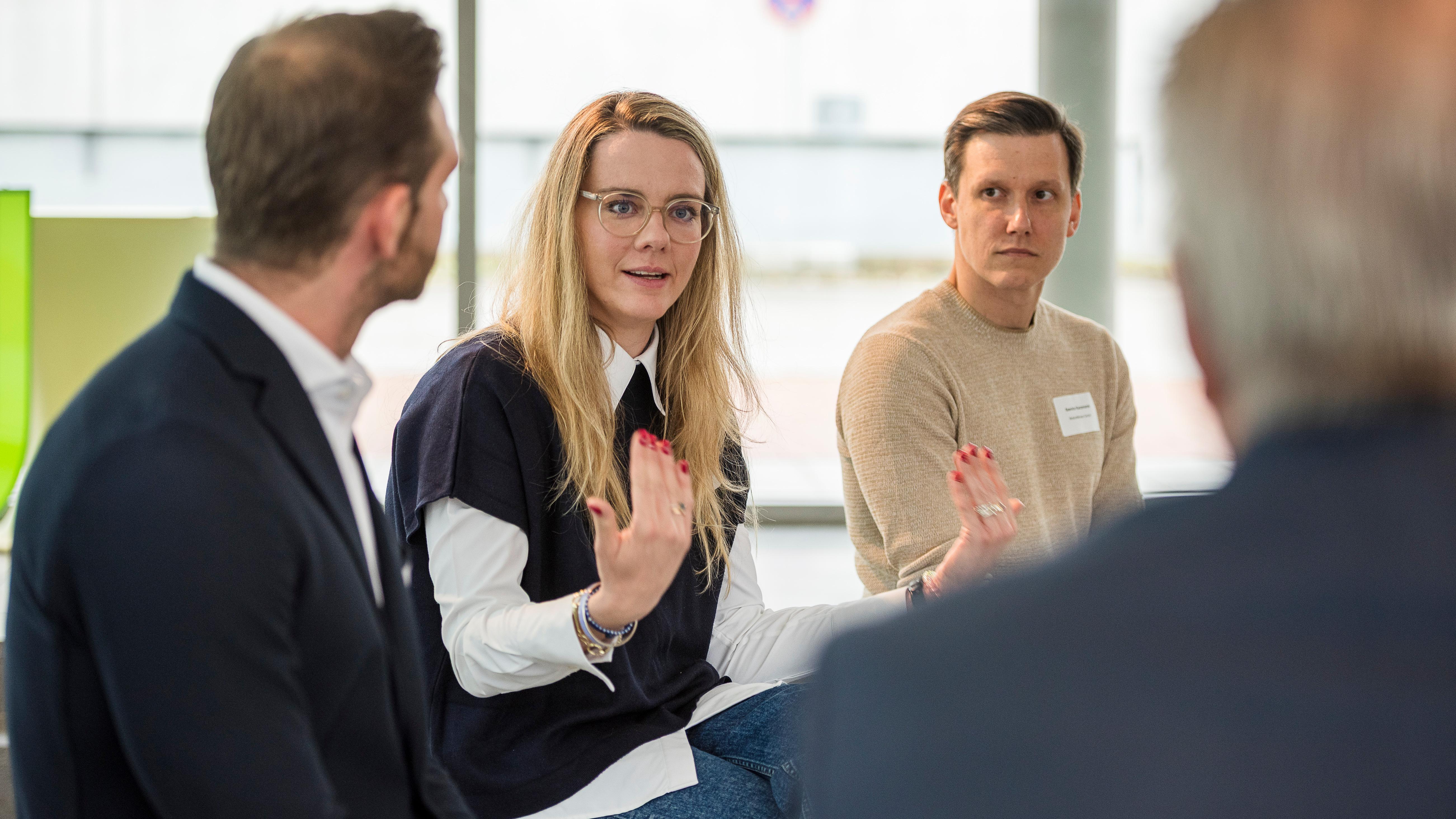 Diskussionsrunde beim Jahrestreffen der Unipreneurs. Zu sehen sind 3 Personen. Eine blonde Frau in der Mitte zwischen zwei Männern
