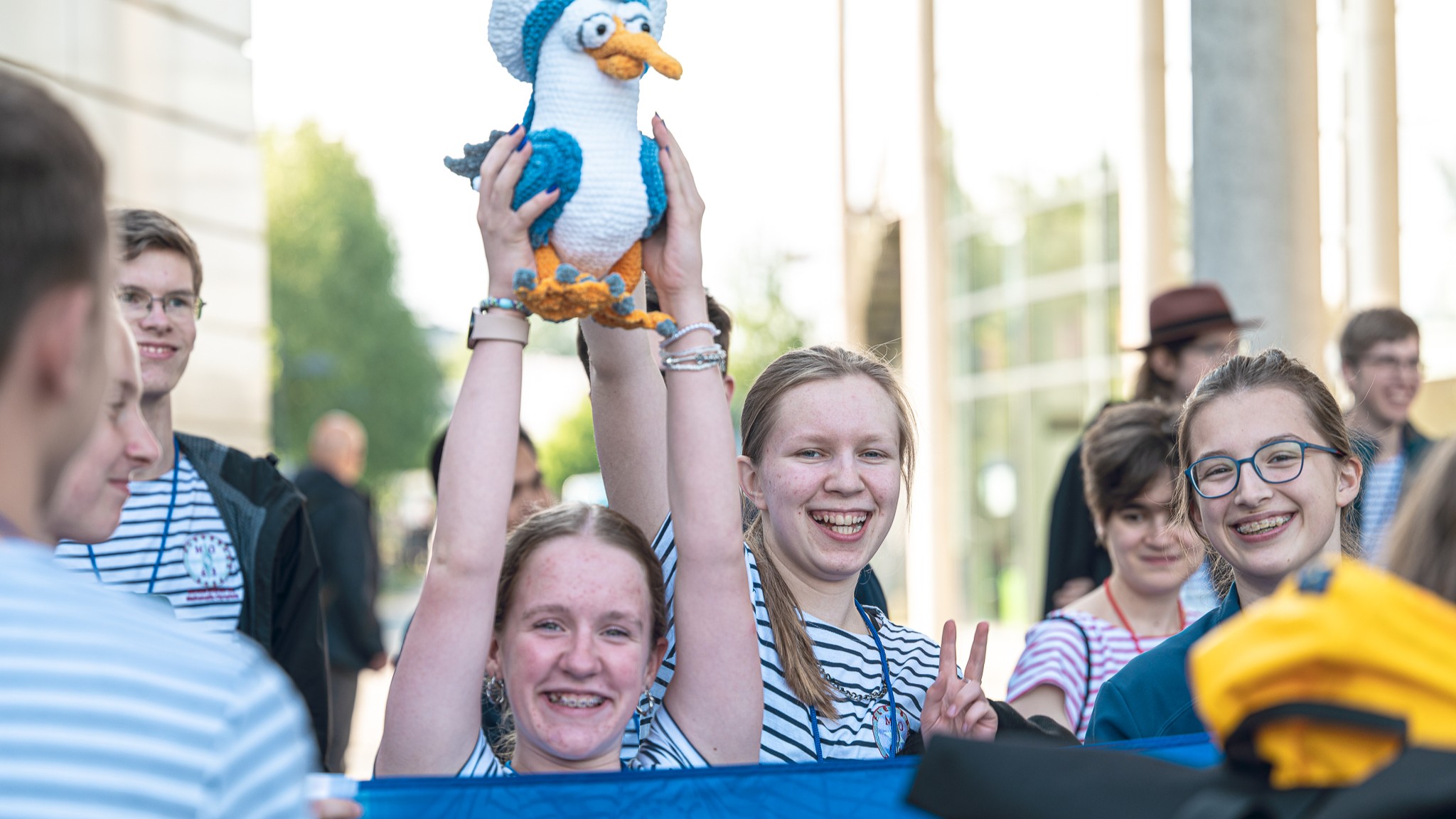 Teilnehmerinnen der Bundesrunde der Mathematik-Olympiade 2024 in Flensburg halten das Maskotchen des Wettbewerbs hoch