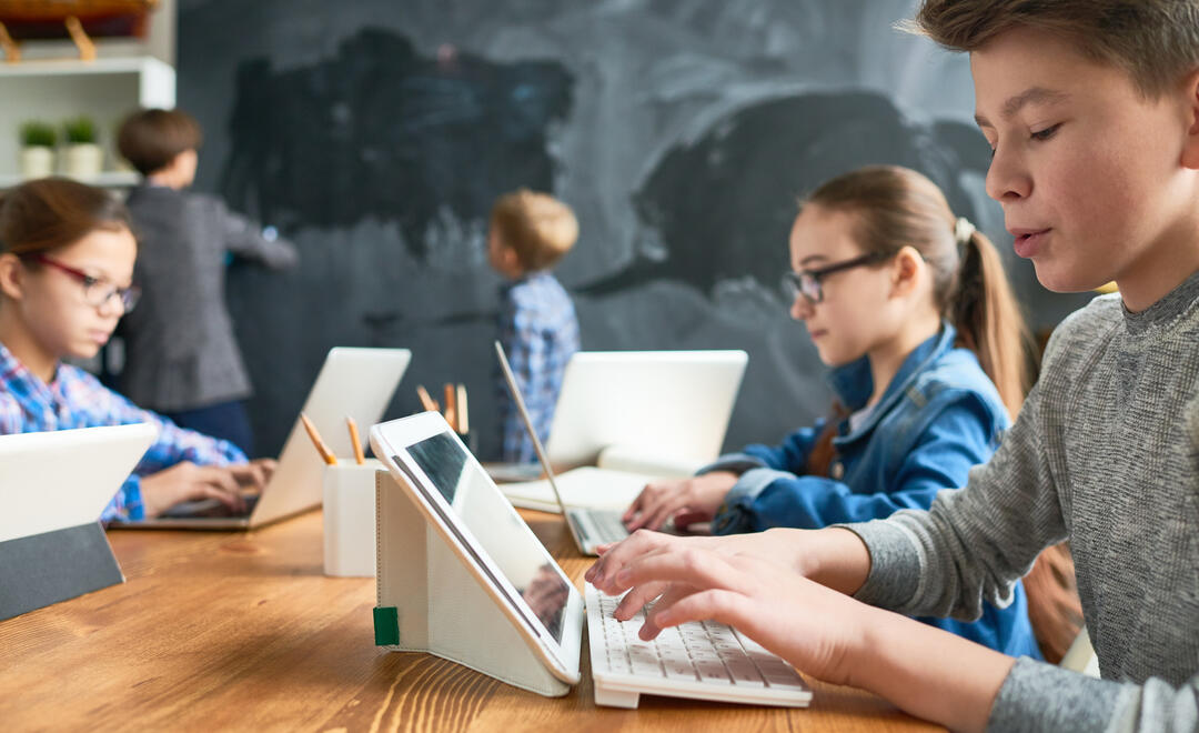 Kinder sitzen im Klassenzimmer vor dem Tablet 