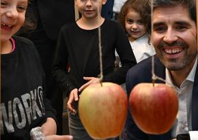 Sven Teuber, Bilcungsminister Rheinland-Pfalz, bei einem MINT-Experiment mit Äpfeln. Mehrere Grunsschulkinder schauen zu