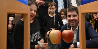 Sven Teuber, Bildungsminister Rheinland-Pfalz betrachtet mit zwei Schülerinnen und einem Schüler ein MINT-Experiment mit zwei Äpfeln