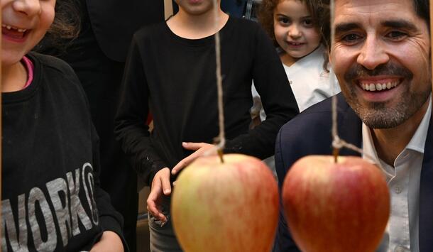 Sven Teuber, Bilcungsminister Rheinland-Pfalz, bei einem MINT-Experiment mit Äpfeln. Mehrere Grunsschulkinder schauen zu