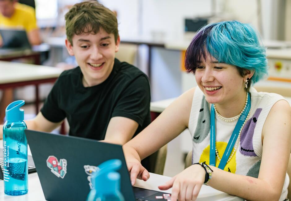 Zwei Jugendliche sitzen vor einem Laptop bei der Deutschen SchülerAkademie